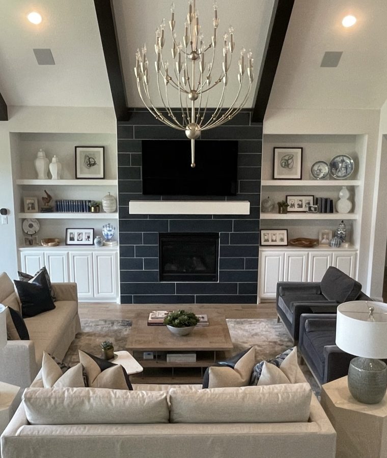 A modern living interior provides a comforting space to relax, set off by a sophisticated fireplace and a beautiful chandelier.