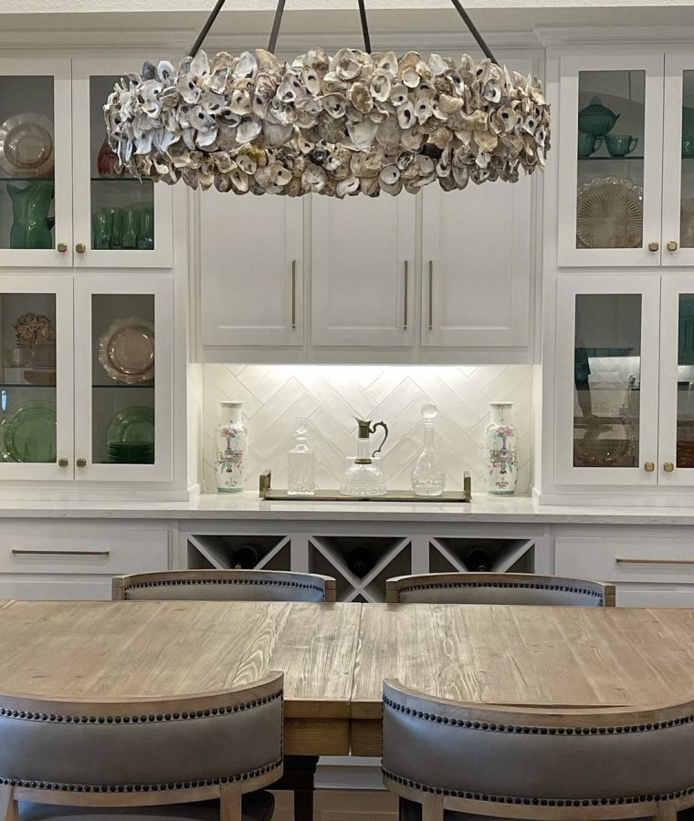 A beautiful kitchen breakfast nook includes a stylish chandelier made with seashells and decorative cabinets with gorgeous hardware.